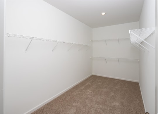 a spacious closet with white walls and hanging racks