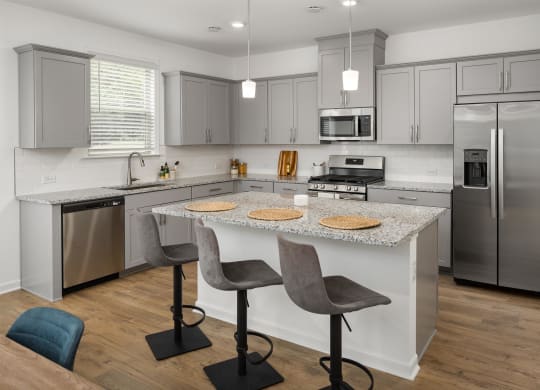 a kitchen with stainless steel appliances and an island with two chairs