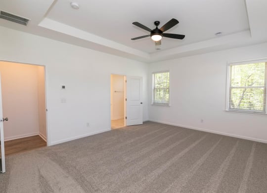 an empty living room with a ceiling fan and white walls