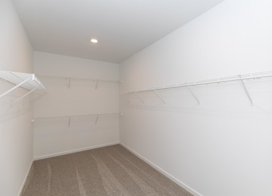 a room with white walls and a closet with white hangers