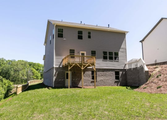 the back of the house has a large lawn and a deck