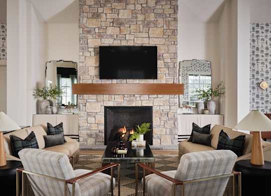Inviting clubhouse living room featuring cozy seating, a fireplace, and a large TV for entertainment.