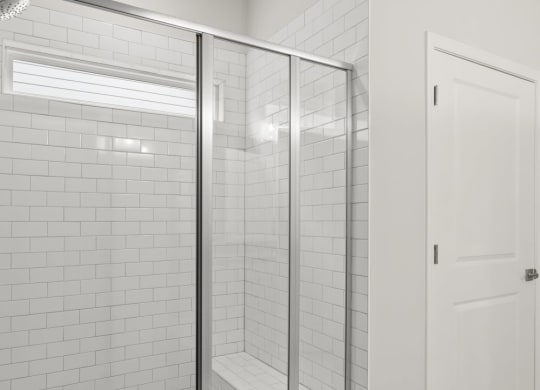 a white tiled bathroom with a shower and a white door