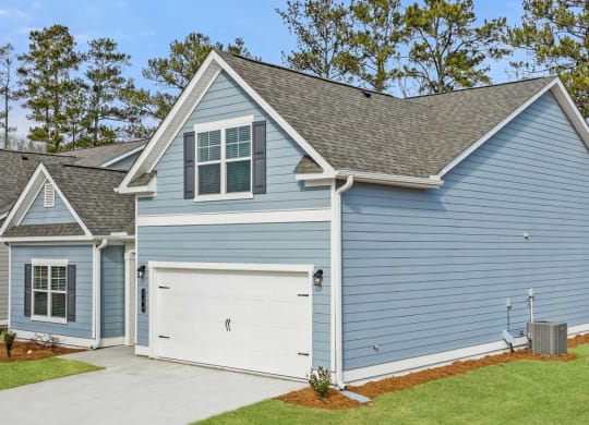 a blue house with a white garage door and a lawn