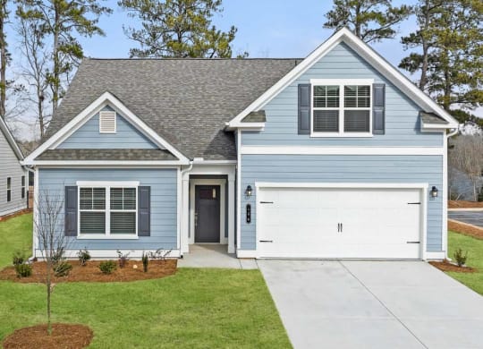 the front of a blue house with a white garage door
