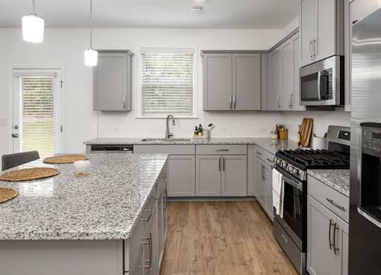 Spacious kitchen with an island, ample storage, stainless steel appliances and view into the living room.