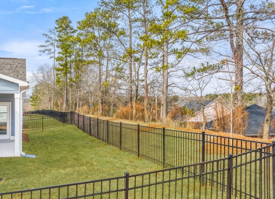 the front yard of a house with a fence and a yard with trees