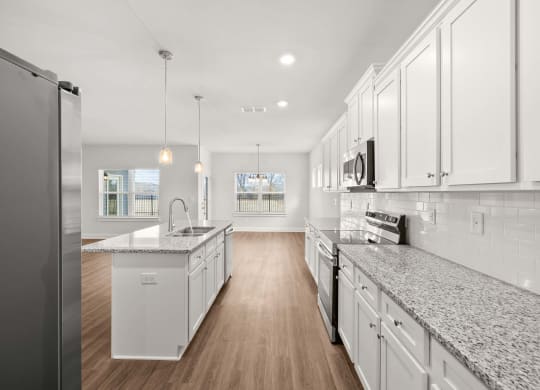 a large kitchen with marble counter tops and white cabinets