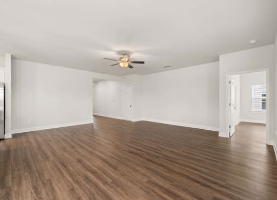 an empty living room with white walls and a ceiling fan