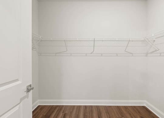 the closet in a bedroom with white walls and a wood floor