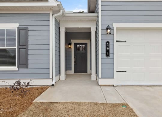 the front entrance to a blue house with a white garage door
