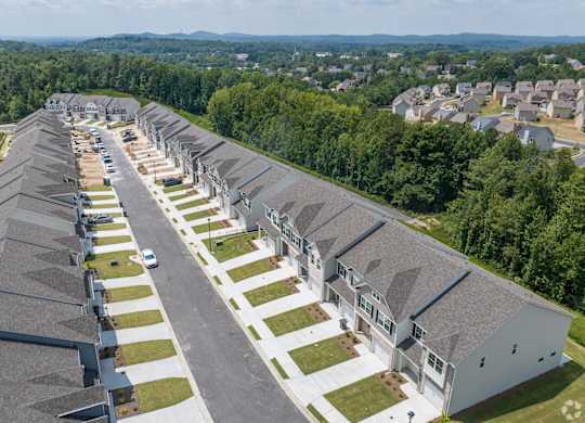 A long row of houses with a car parked in the driveway of the first house.