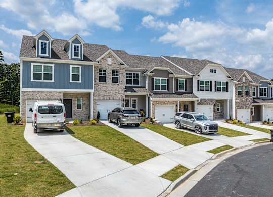 A row of houses with cars parked in front.