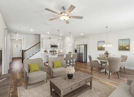 a living room with couches and chairs and a table and a ceiling fan