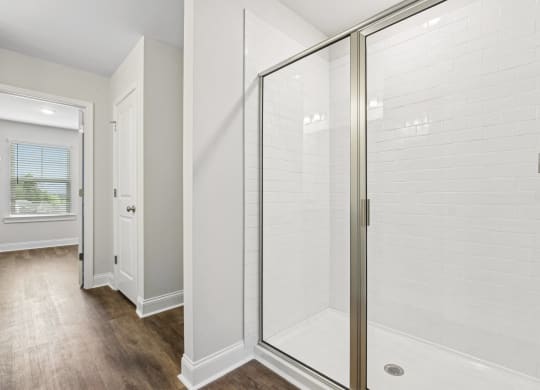 a white shower in a bathroom with a wood floor