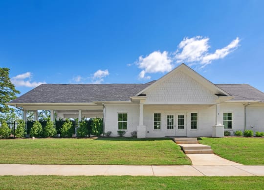 a white house with a green lawn and a blue sky