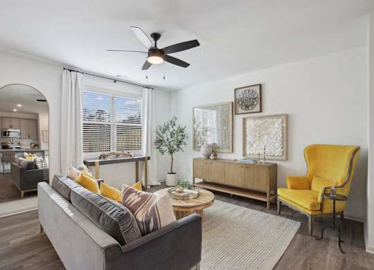 Bright living room featuring a large couch and abundant natural light through expansive windows.