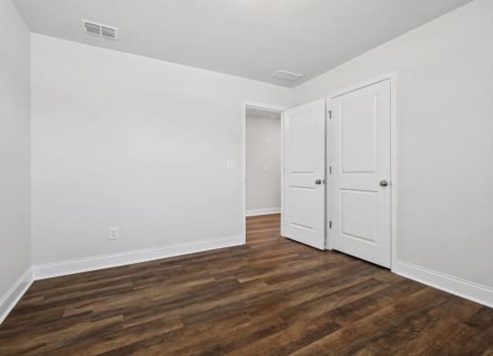 a bedroom with white walls and wood flooring and white doors