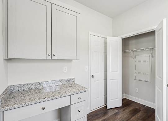 a kitchen with white cabinets and a marble counter top