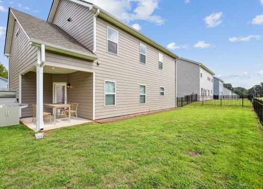 the back of a house with a yard and a grill