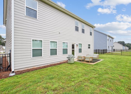 the back of a white house with a patio and grass