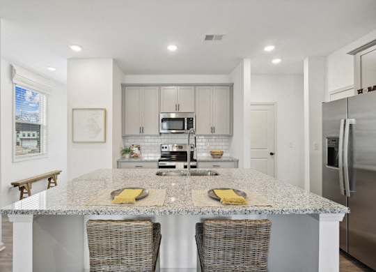 View of the kitchen and entry hallway. Offering bar seating, plenty of cabinet space and granite countertops.