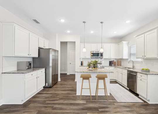 a large kitchen with white cabinets and stainless steel appliances