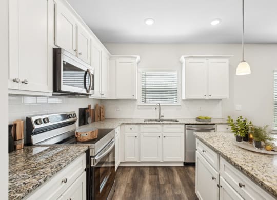 a white kitchen with marble counter tops and white cabinets