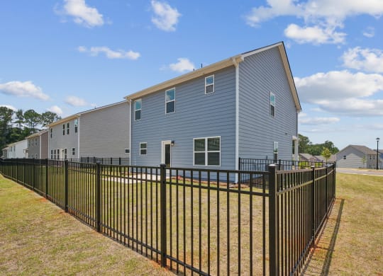 a blue house with a fence in front of a yard