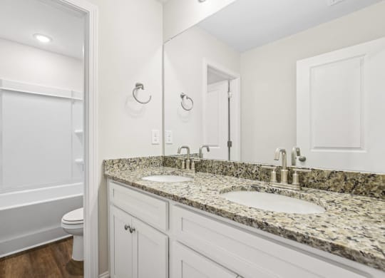 a bathroom with white cabinets and granite counter tops and a sink and a toilet