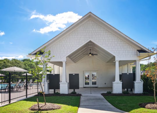 the front of a white church with a black fence and grass
