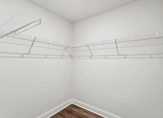 an empty closet with white walls and a wood floor