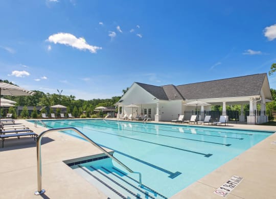 a swimming pool with chairs and a building in the background