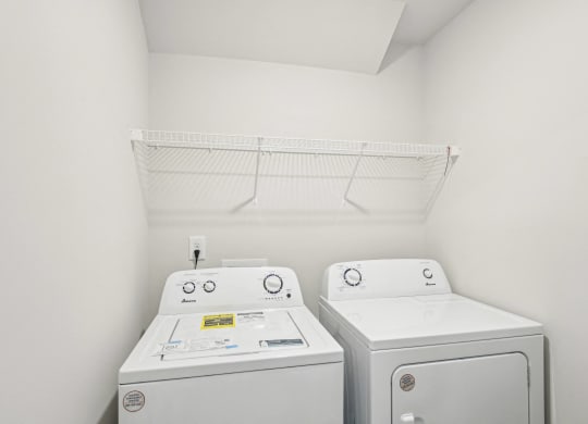 a white laundry room with two washes and a dryer