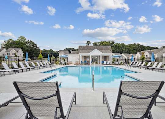 a swimming pool with chairs and a building in the background