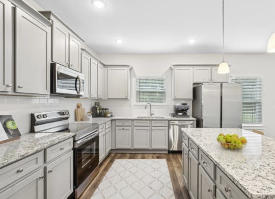 a large kitchen with white cabinets and marble counter tops