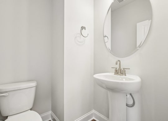 a white bathroom with a white toilet and a sink and a mirror