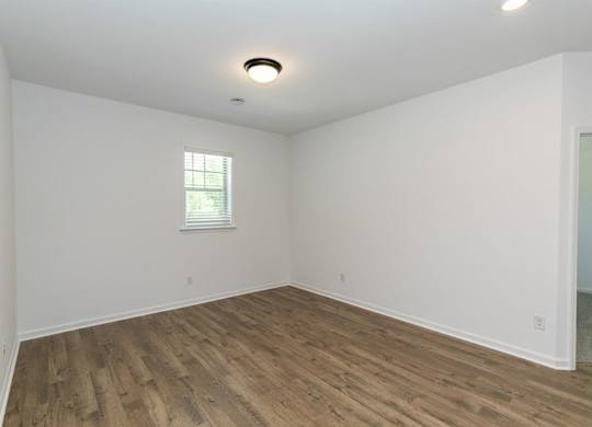 Bedroom with hardwood flooring and windows for natural lighting.