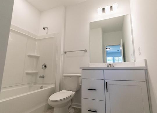 A white bathroom with a toilet, sink, and bathtub.