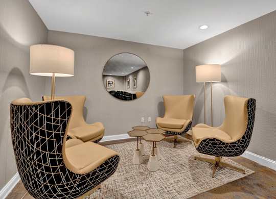 A living room with a black chair and a round mirror on the wall.