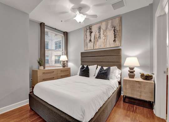 A bedroom with a large bed, two nightstands, and a ceiling fan.