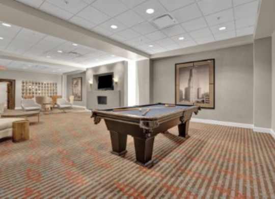 A pool table is in the middle of a room with a carpeted floor.