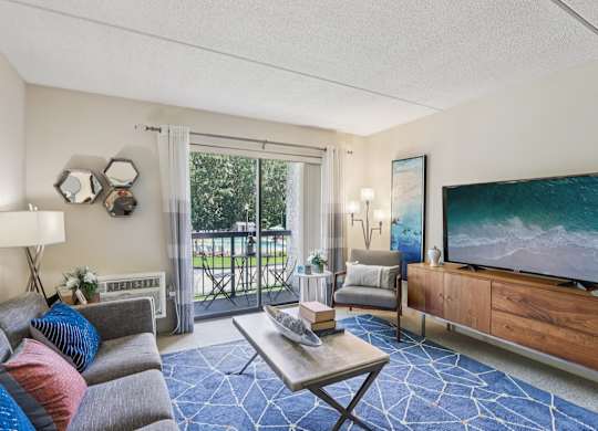 A living room with a grey couch, a coffee table, a television, and a painting on the wall.