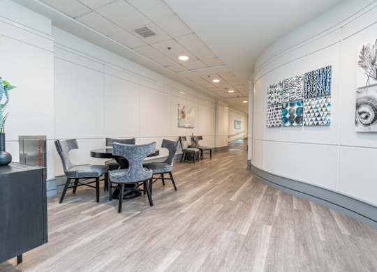 a room with a table and chairs on the left and a hallway on the right