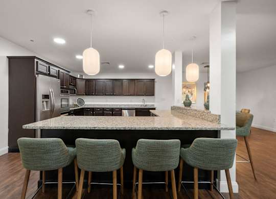 A kitchen with a large island and four green chairs.