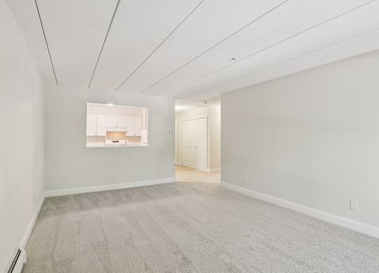 A large empty room with carpeted floor and white walls.