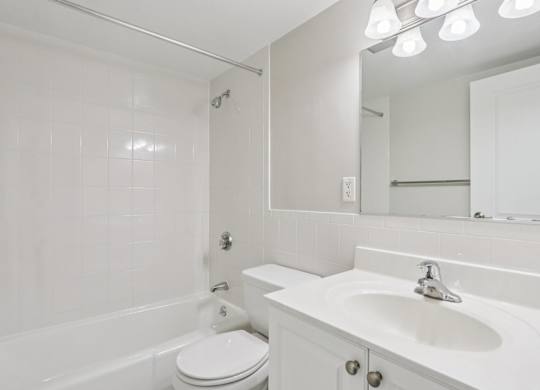 A white bathroom with a toilet, sink, and bathtub.