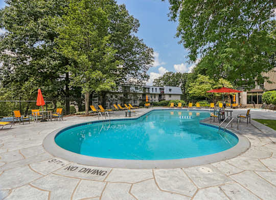 A round swimming pool surrounded by trees and chairs.