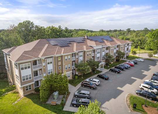 A large apartment complex with a parking lot in front.