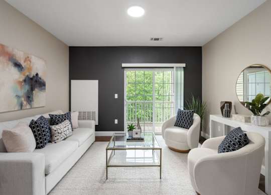 A modern living room with a white sofa, two armchairs, and a glass coffee table.